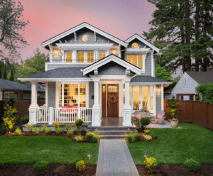 A small but luxurious suburban American home is lit from within in the early evening