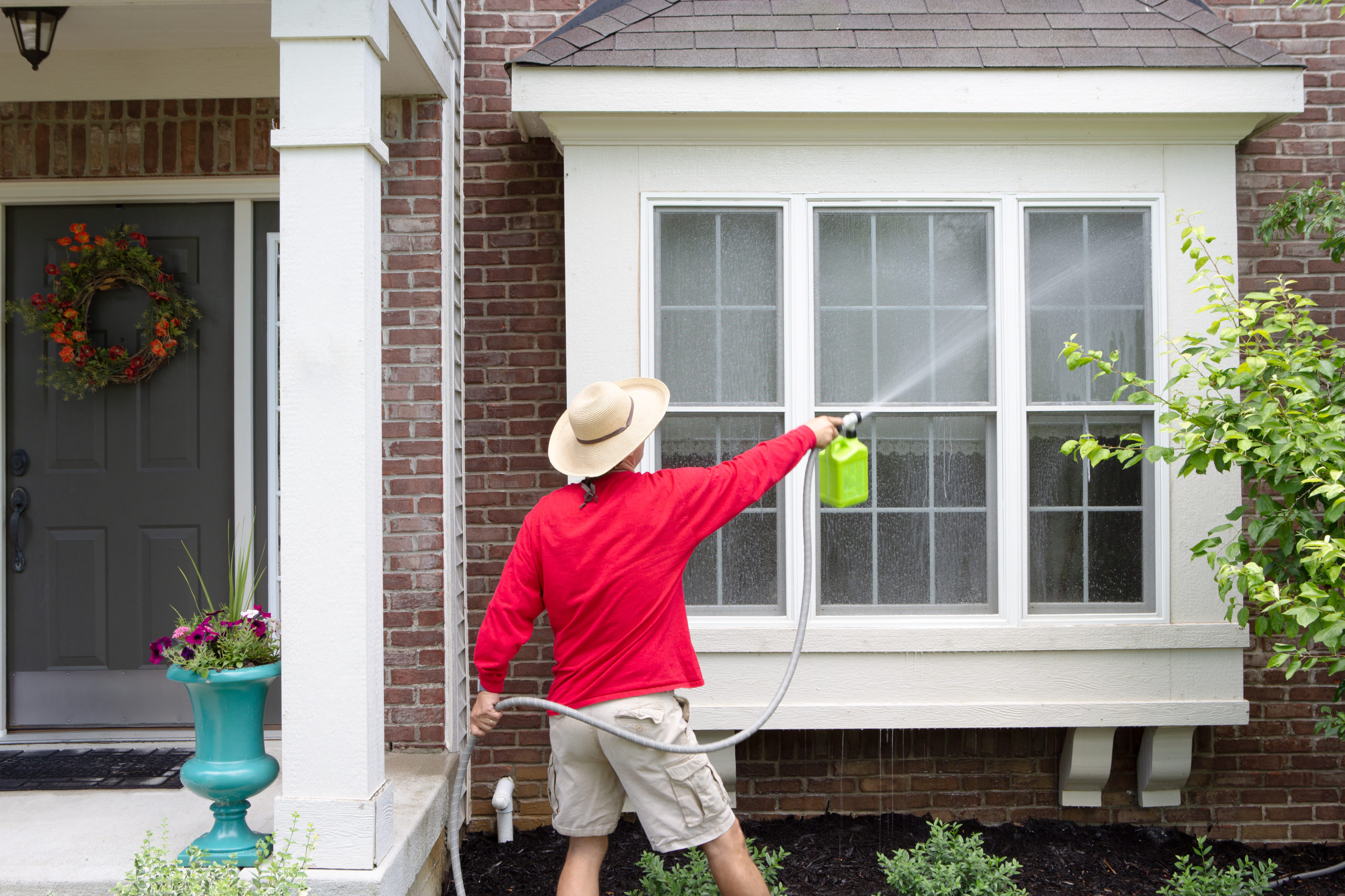 The window is being cleaned. Exterior residential Window Cleaning. Garden House Cleaning service. Exterior House washing. Home Exterior Cleaning.