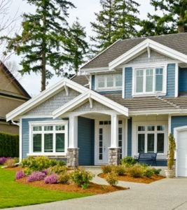 A beautiful home with blue siding and plantings outside